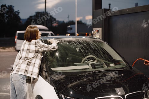 Preview: Woman washing her car with a rug in the car wash station