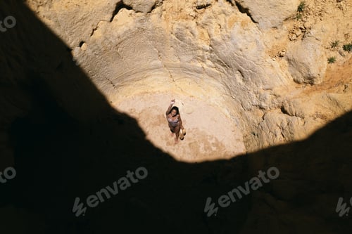 Preview: woman standing in rocky cave with hole in summer