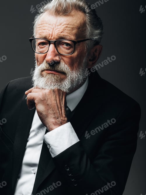 Preview: Pensive old business man in formal black suit, keeps palms near his chin.