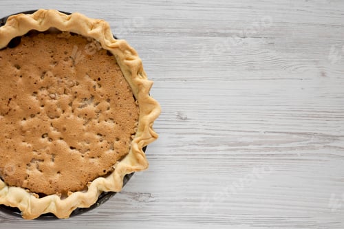 Preview: Home-baked Chocolate Walnut Derby Pie on a white wooden table, top view.