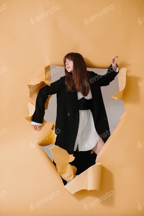 Preview: A young beautiful girl in a fashionable outfit poses on a torn paper background.