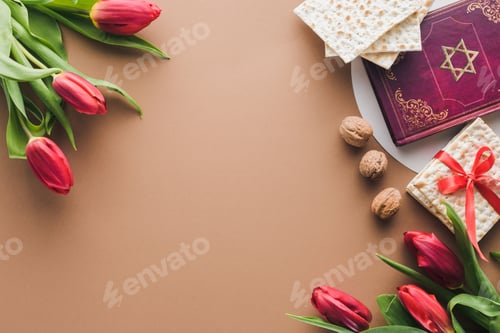 Preview: top view of traditional book with text in hebrew, bouquets of red tulips and matza on table