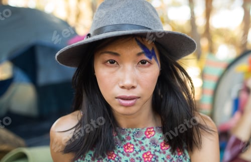 Preview: Woman in hat with face paint enjoying outdoor music festival atmosphere