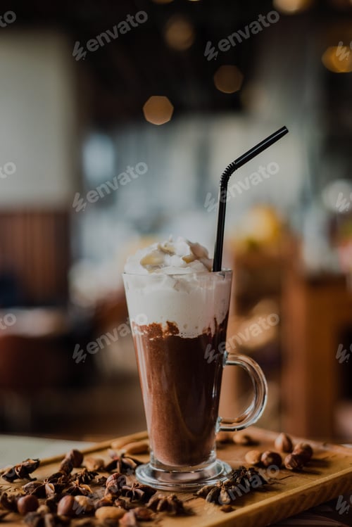 Preview: Close-up hot chocolate in a tall glass with whipped cream on a wooden board in a cafe