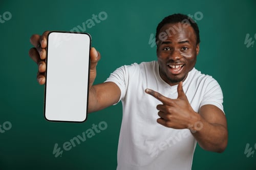 Visualização: telefone, espaço vazio em branco. Homem afro-americano está de pé contra um fundo verde no estúdio