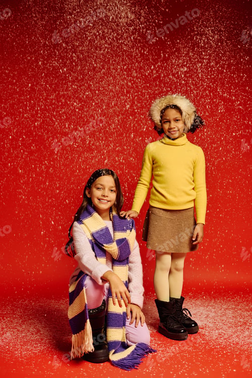 Preview: Joyful little girls celebrate Christmas in cozy outfits against a festive snowy backdrop