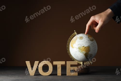 Preview: Wooden letters, hand and globe on table on brown background, space for text