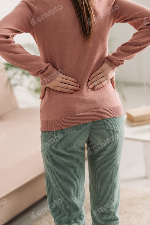 Preview: cropped view of woman holding hands on loin while suffering from back pain
