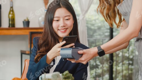 Preview: Young Asian business women pay contactless at coffee shop.