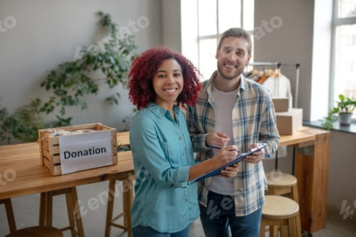 Preview: Young girl and man standing writing in notebook.