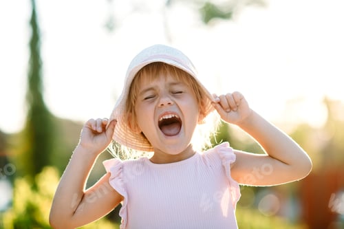 Preview: Happy and smiling blonde toddler girl in pink dress and hat. Happiness