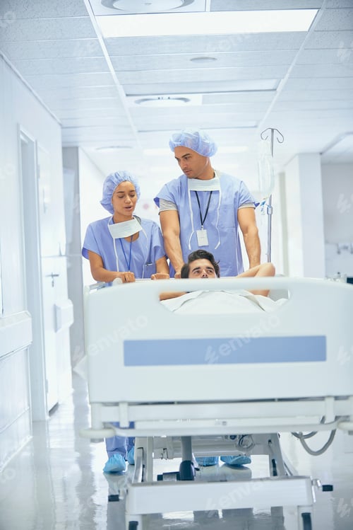 Preview: Doctors wearing surgical scrubs pushing patient in hospital bed