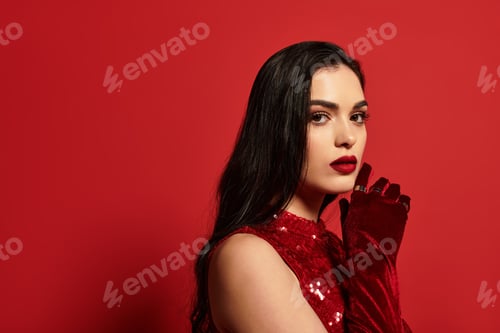 Preview: Striking beauty with red gloves and lips poses elegantly in vibrant studio setting