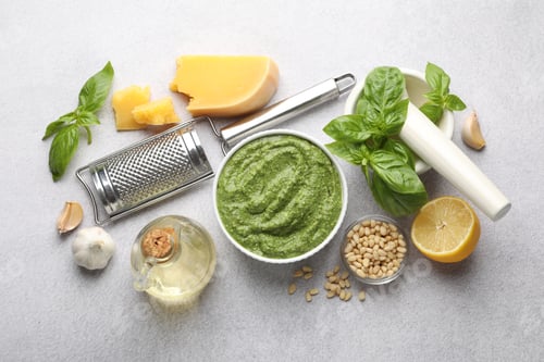 Preview: Fresh pesto sauce in bowl and ingredients on light grey table, flat lay