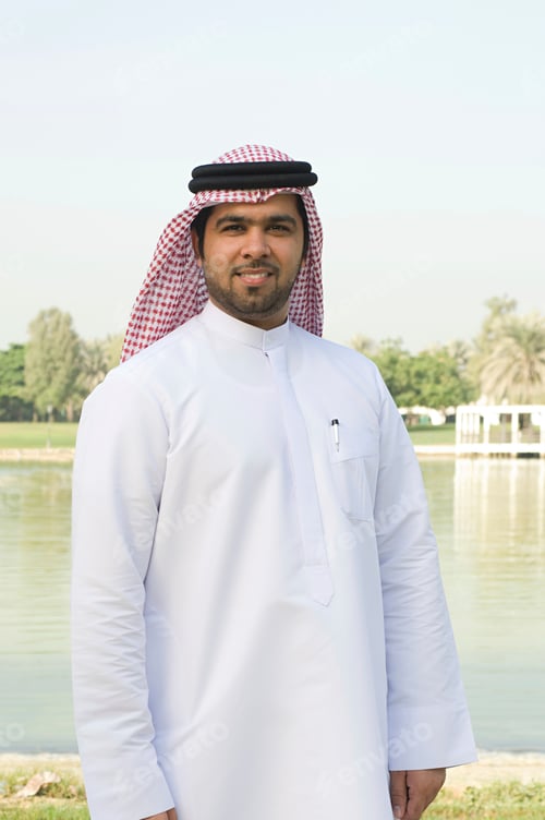 Preview: Man in traditional attire stands before a serene lake setting.