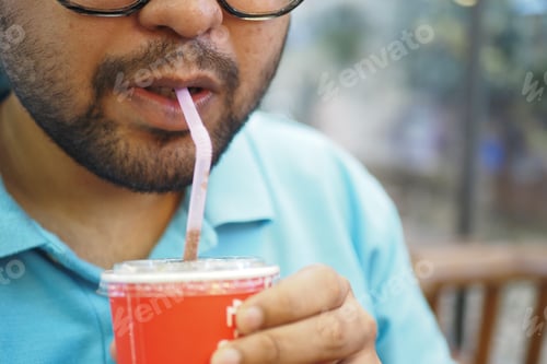 Preview: Man enjoys cold drink in casual setting at cafe