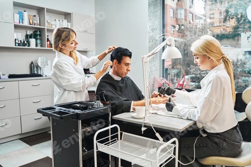 Preview: Beauty parlour visitor with smartphone having his hair cut