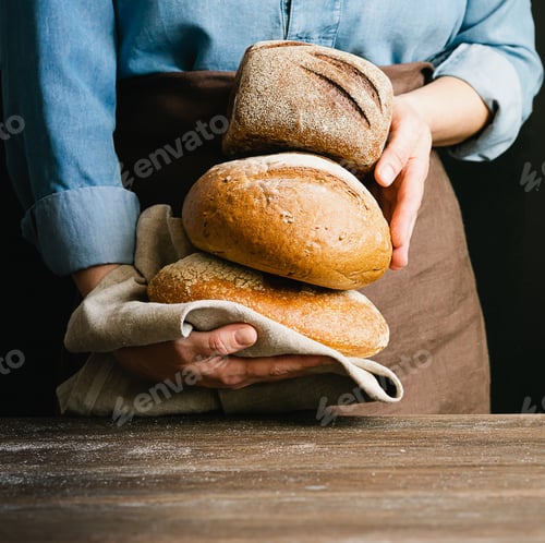 Preview: Woman holds in her hands lot of rolls of fresh bread. Rustic home bakery style