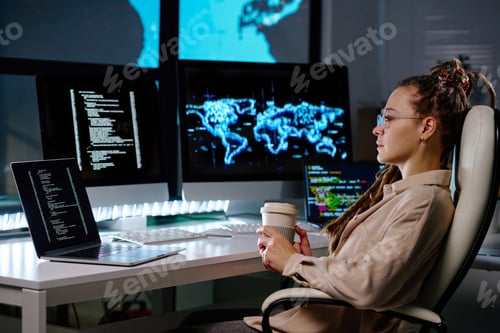 Preview: Young serious businesswoman with cup of coffee sitting in armchair