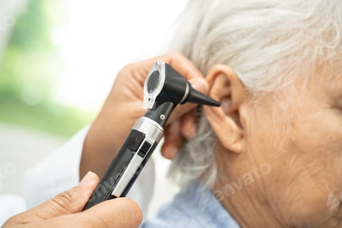 Preview: Audiologist or ENT doctor use otoscope checking ear of asian senior woman patient treating