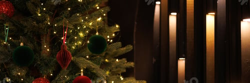 Preview: Close-up of a Christmas tree with red balls and bokeh in the background.