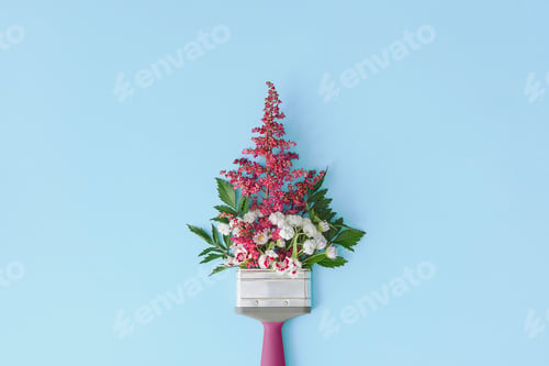 Preview: Creative floral arrangement on a blue background with a copy space. Paintbrush with flowers.