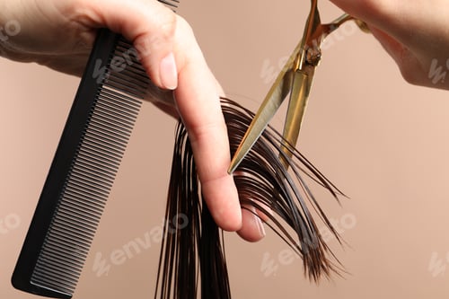 Preview: Hairdresser cutting client's hair with scissors on light brown background, closeup