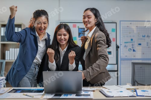 Preview: Three young asian businesswomen are celebrating success, looking at laptop screen, raising fists, sh