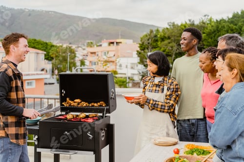 Preview: Happy multigenerational people having fun doing barbecue grill at house rooftop