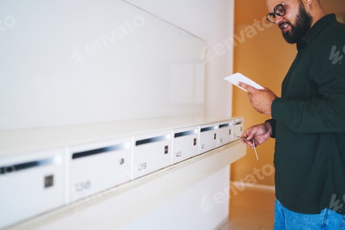 Preview: Man reading letter near postal boxes in house