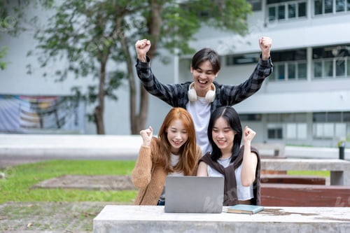 Preview: Three young people are celebrating with their hands raised in the air