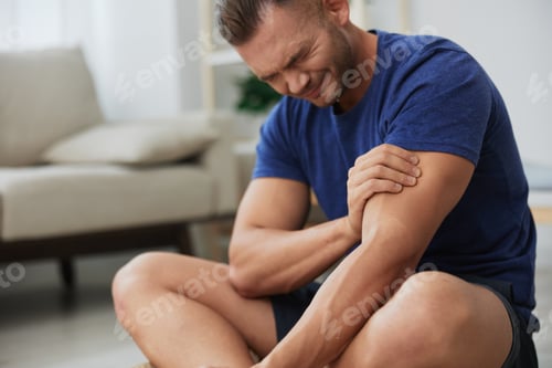 Preview: Man athlete pain and injury back arm and leg at home, sports injury bodybuilder, concept health and