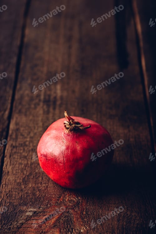 Preview: One red pomegranate on wooden surface