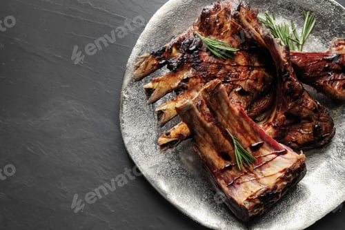 Preview: Delicious grilled ribs served on black table, top view. Space for text
