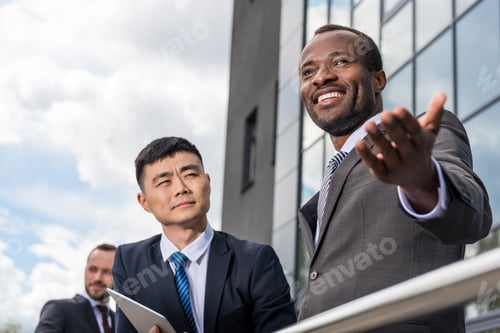 Preview: multicultural business team meeting outdoors near office building