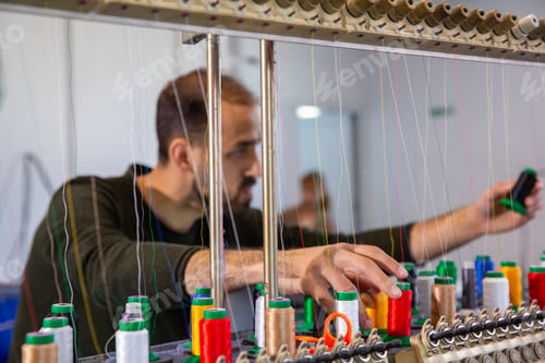 Preview: Worker at the textile factory that arranges the multicolored yarn reels