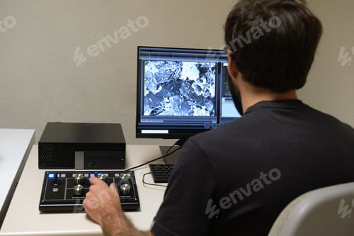 Preview: Young man scientist working with scanning electron microscope