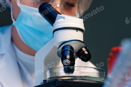 Preview: Woman scientist looking through a microscope in laboratory