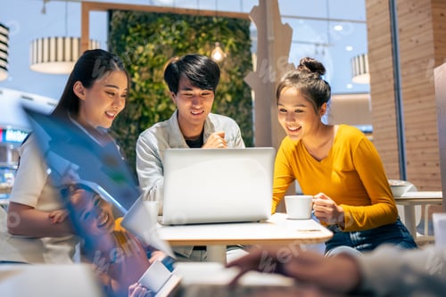 Preview: Group of Asian friends talking and using laptop computer in restaurant.