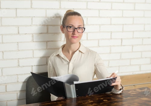 Preview: a young business woman is sitting at a desk with documents