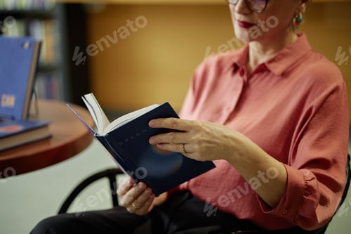 Preview: Middle Aged Caucasian Woman Reading Book While Sitting in Library