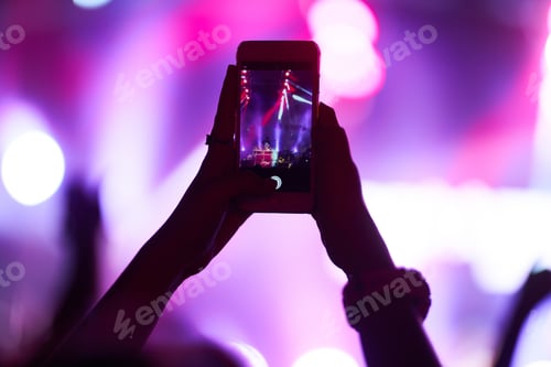 Preview: Hand with a phone records live music festival. People taking photographs with smart phone concert.