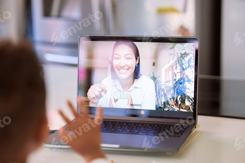 Preview: Little girl on a video call with her teacher using a laptop. Young female teacher doing a virtual l
