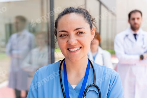 Preview: Caring medical professional smiling with diverse healthcare team standing outside hospital building