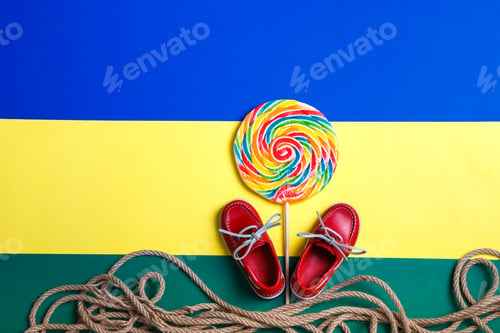 Preview: Small red boat shoes near big multi-colored lollipop