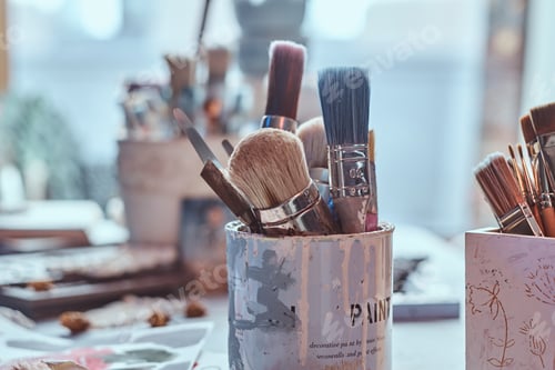 Preview: A lot of different brushes on artist's table in jars. There are artistick's mess on the table
