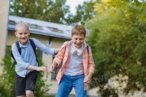 Preview: Happy caucasian children running from school with backpacks on sunny day. Begining of academic year.