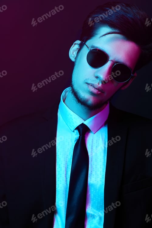 Preview: Neon studio portrait of young man wearing trendy sunglasses and elegant ?ostume. Elegant businessman