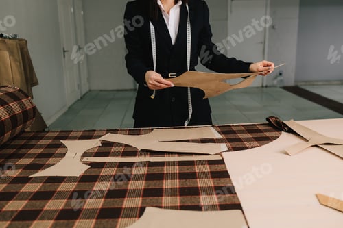 Preview: Designer sets paper patterns on fabric, ensuring proper layout for apparel.