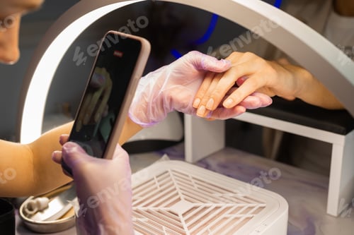 Preview: Nail technician photographing finished manicure on female